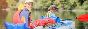 Happy kids kayaking on the river on a sunny day during summer vacation