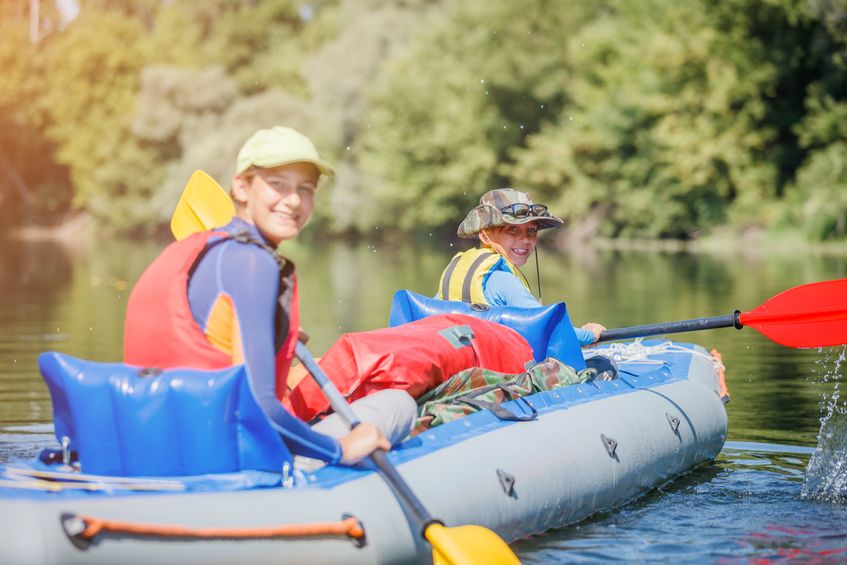 Happy kids kayaking on the river on a sunny day during summer vacation