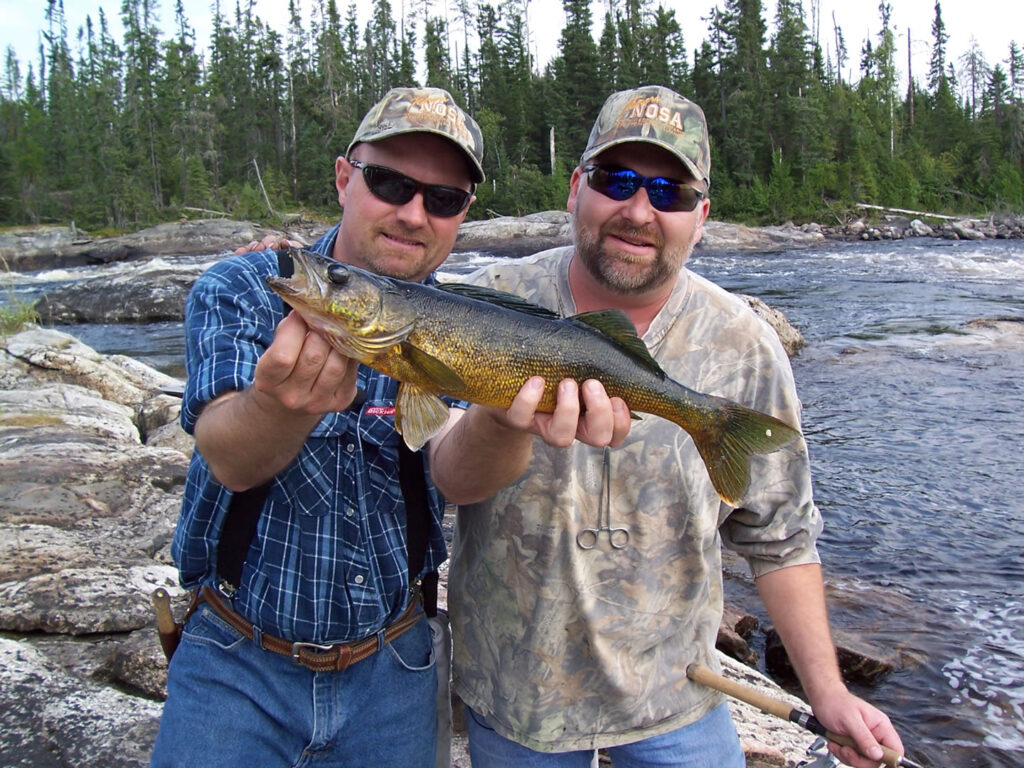 two men holding fish next to ogoki reservoir