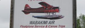 Sign for Mattice Lake Outfitters advertising fly-in camps and floatplane service, featuring an image of a red floatplane.